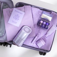 Opened suitcase with passport, skincare products, and Canopy Portable Humidifier