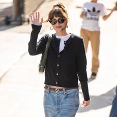 Dakota Johnson wears a black cardigan and straight-leg jeans