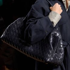 A model carrying a navy blue Bottega Veneta Lauren shoulder bag at the F/W 24 show.