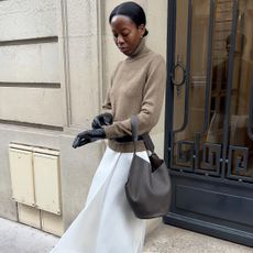 Woman in turtleneck, gloves, and white skirt